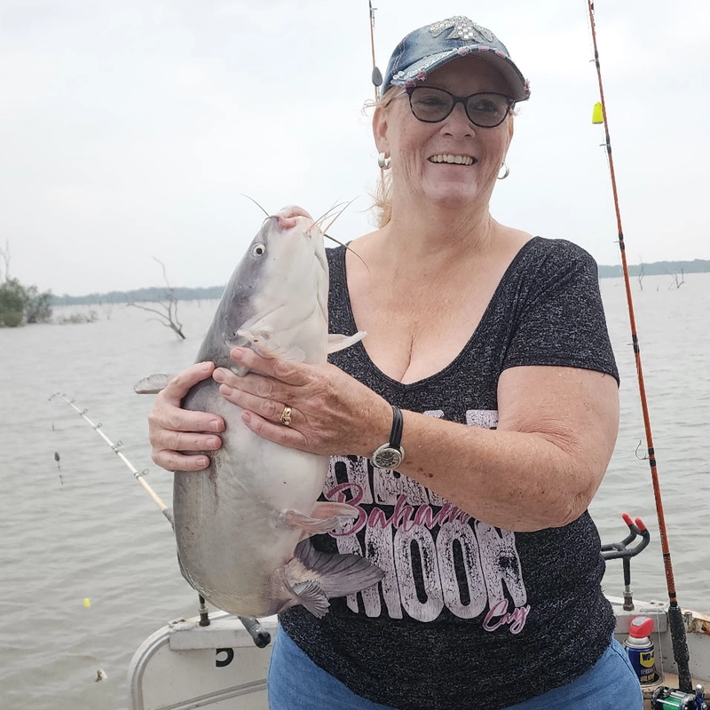 Woman holding a blue catfish on a boat during a successful Lake Tawakoni catfish fishing trip with Thundercove Guide Service in May 2026.